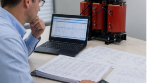 Engineer using transformer calculator with load schedule and electrical drawings